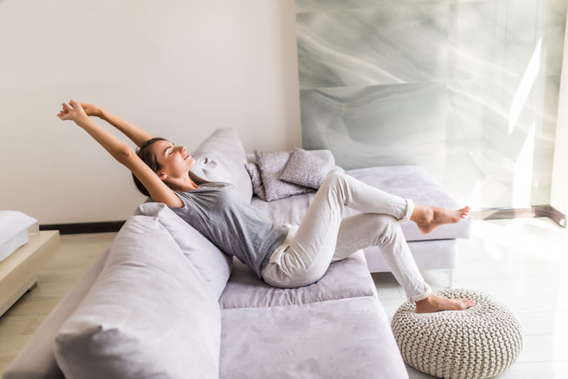 mujer sonriente relajandose en el sofá