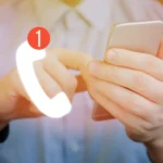Persona sosteniendo un teléfono móvil con icono de llamada perdida