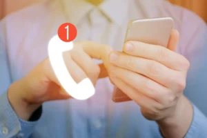 Persona sosteniendo un teléfono móvil con icono de llamada perdida
